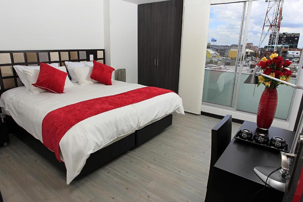 1 dormitorio con 1 cama grande con almohadas rojas en AW Hotel Ariston en Bogotá