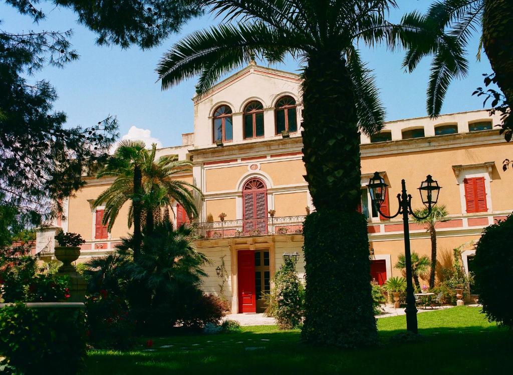a building with palm trees in front of it at Villa Fenicia in Ruvo di Puglia