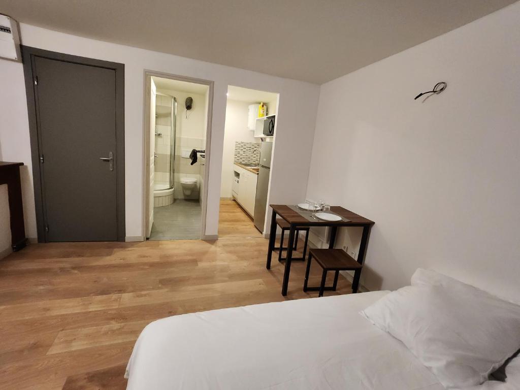 ein Schlafzimmer mit einem Bett und einem Tisch sowie ein Badezimmer in der Unterkunft Studio cozy centre ville rdc in Bar-le-Duc