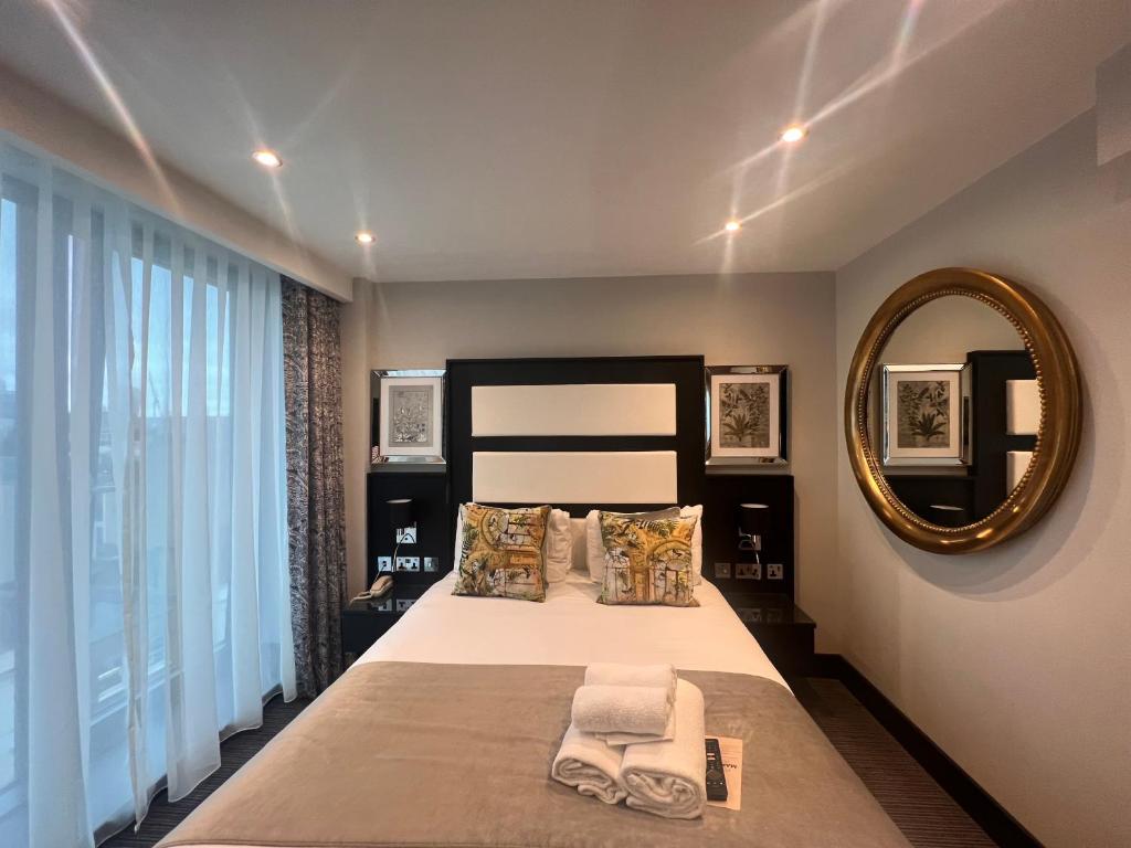 a bedroom with a large bed and a mirror at Hatton Garden Hotel in London