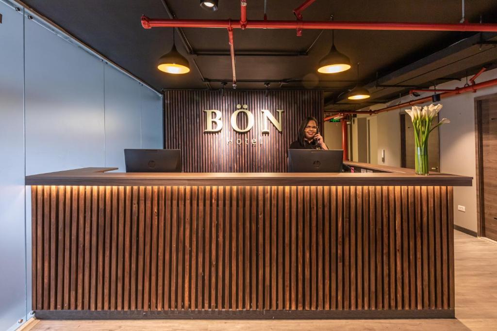 a woman standing behind a bar with two laptops at Bon 17 Hotel By SHG in Bogotá