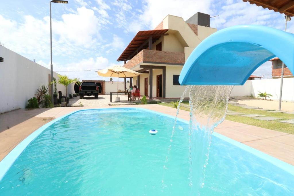 a blue swimming pool with a water fountain at POUSADA SOLAR DOS MOREIRAS in Guajiru