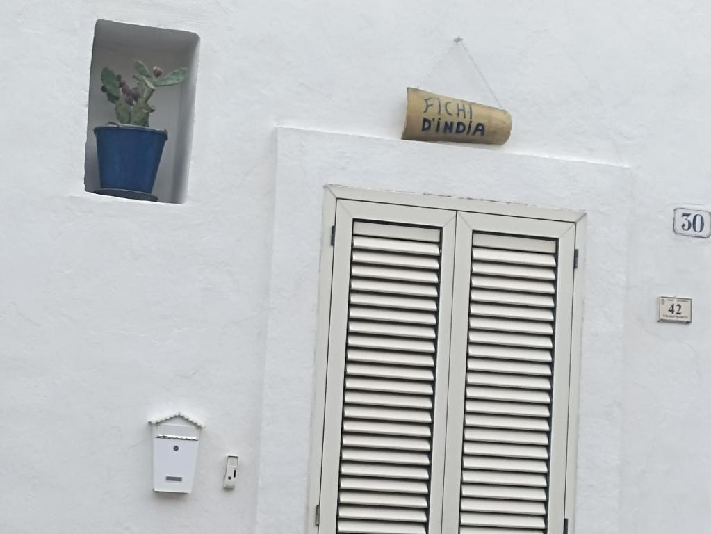 un edificio bianco con una porta e un cartello sopra di Fichi d india a Cellino San Marco