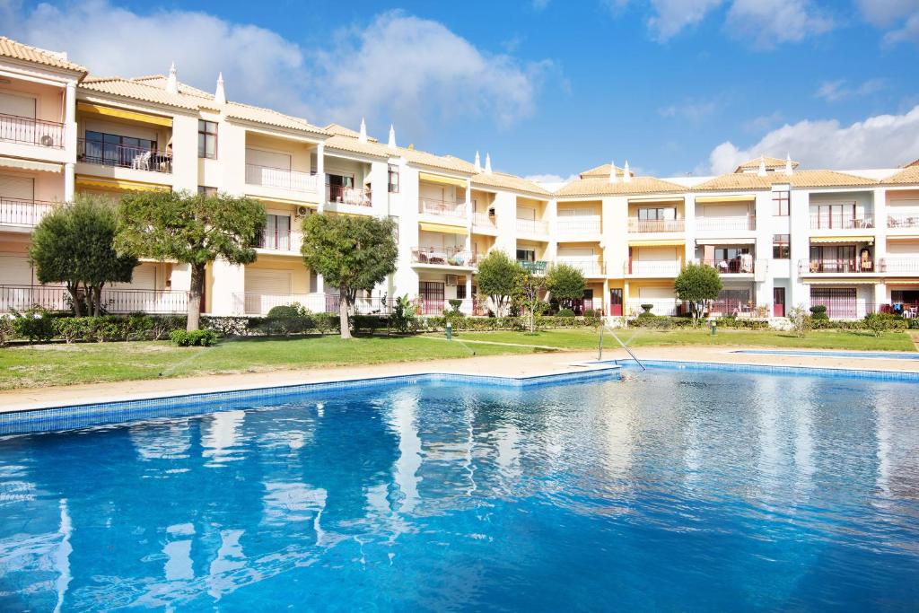 uma piscina em frente a um grande edifício de apartamentos em Columbus Beach Apartment em Quarteira