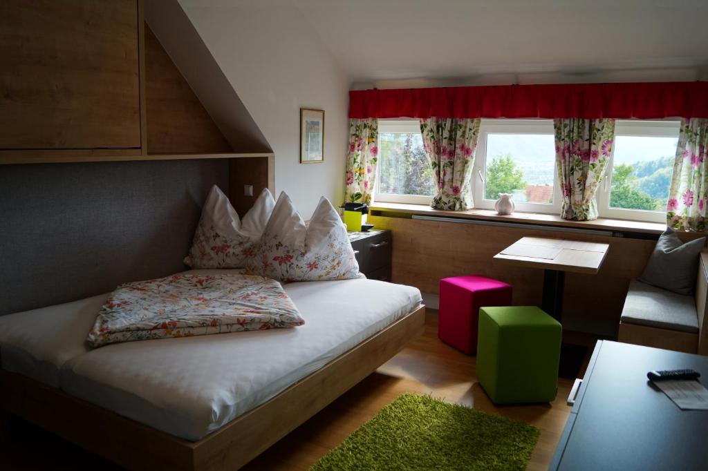 - une chambre avec un lit, un tabouret vert et des fenêtres dans l'établissement Die Bäckerei, à Maria Rain