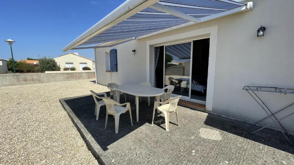 un patio con mesa y sillas junto a un edificio en Villa La Grande Vallée en Saint-Gilles-Croix-de-Vie