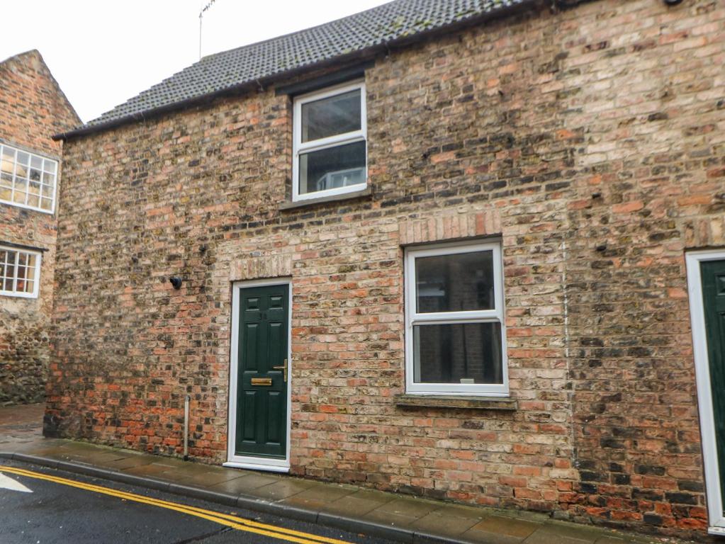a brick building with two windows and a door at Firkin Cottage in Bedale