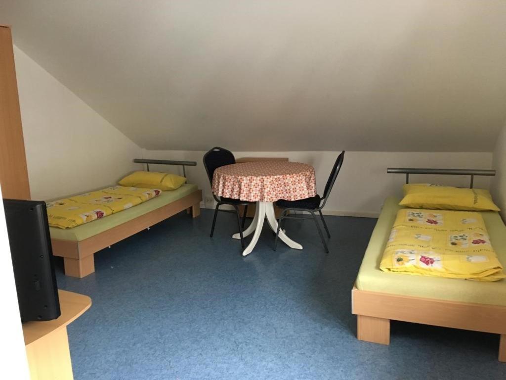 a room with two beds and a table and chairs at Kleine Ferienwohnung in Vöhringen