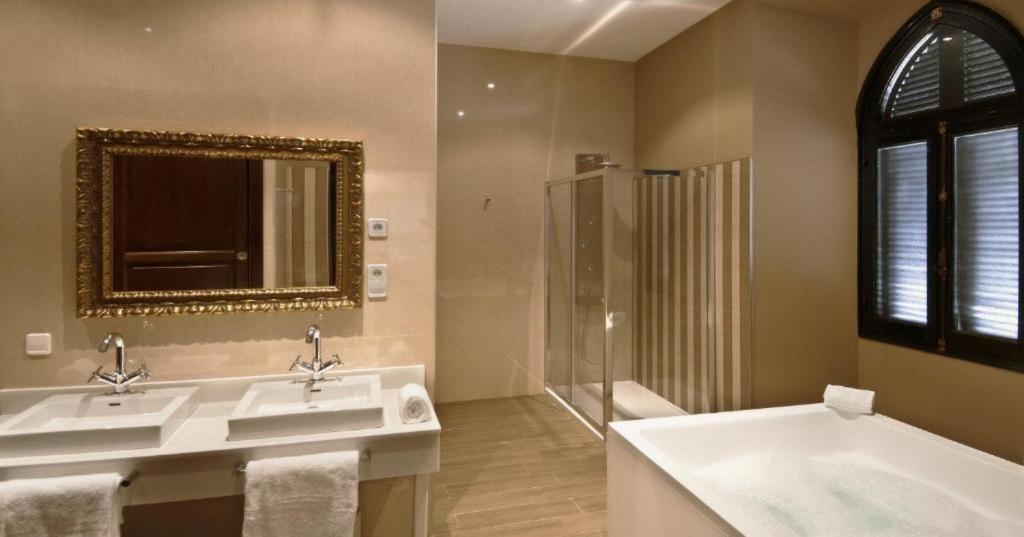 a bathroom with two sinks and a mirror and a shower at La Almoraima Hotel in Castellar de la Frontera