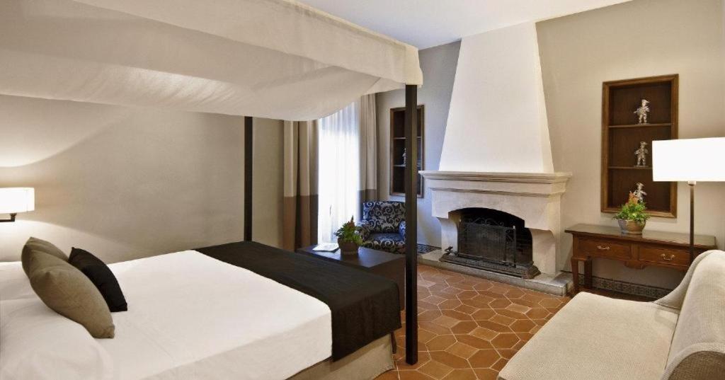 a bedroom with a bed and a fireplace at La Almoraima Hotel in Castellar de la Frontera