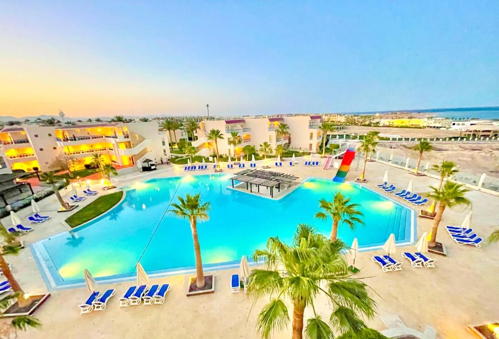 een uitzicht over een groot zwembad met palmbomen en stoelen bij Ivy Cyrene Island Resort in Sharm El Sheikh