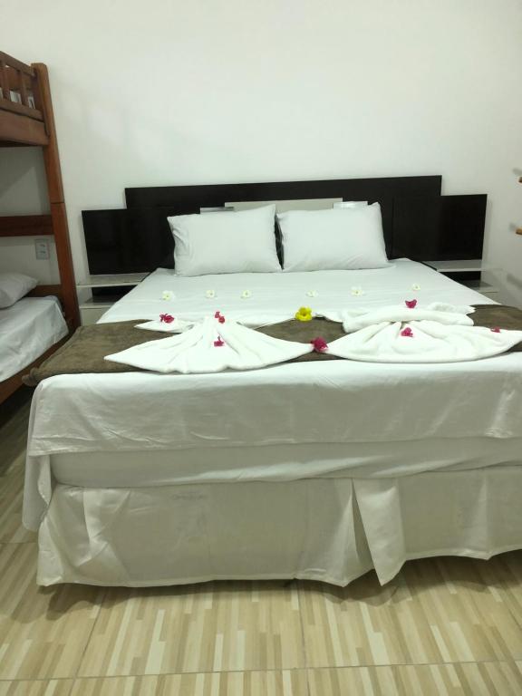ein Bett mit weißer Bettwäsche und Blumen darauf in der Unterkunft Villa Brilho do Sol in Jericoacoara