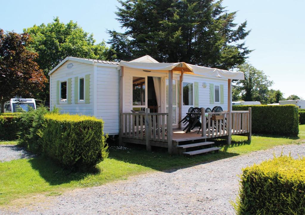 une petite maison blanche avec une véranda et une tente dans l'établissement Camping Le Picard, à Tournières