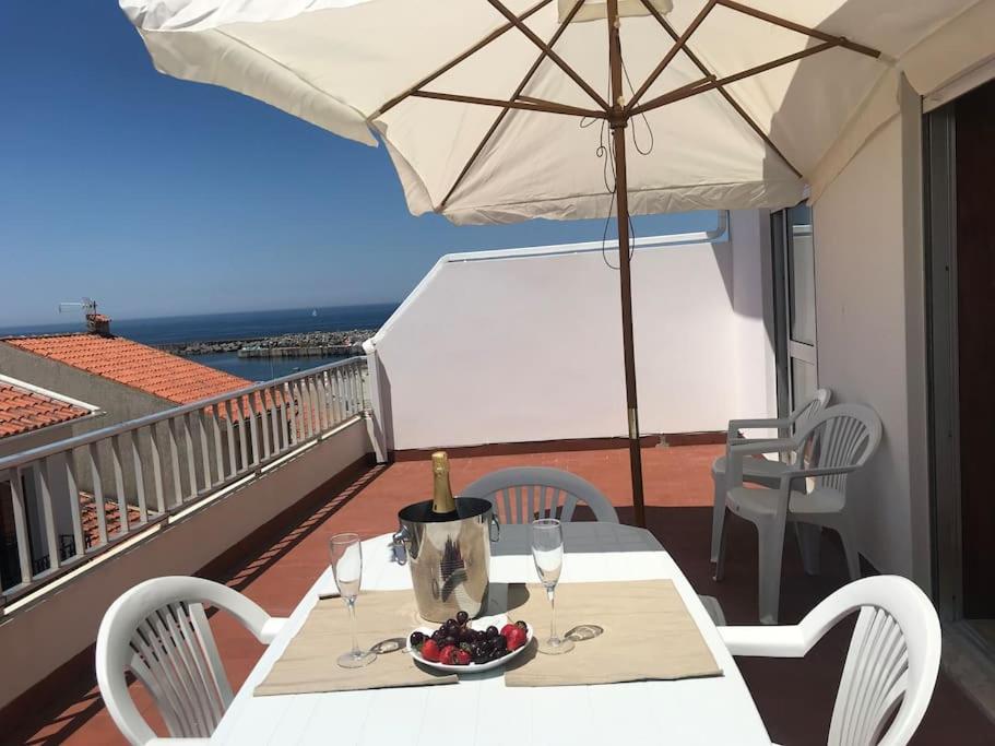 einen Tisch mit Weingläsern und einem Sonnenschirm auf dem Balkon in der Unterkunft A Terraza da Filipa in Vila Praia de Âncora