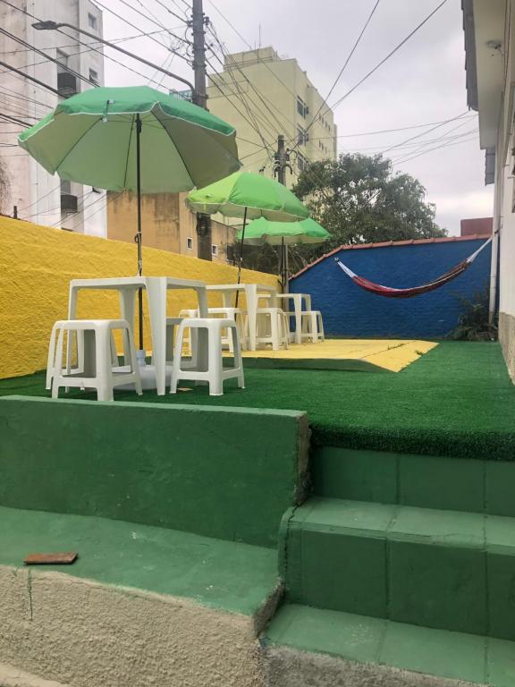 een groep tafels en stoelen met parasols bij Hostel Celine in São Bernardo do Campo