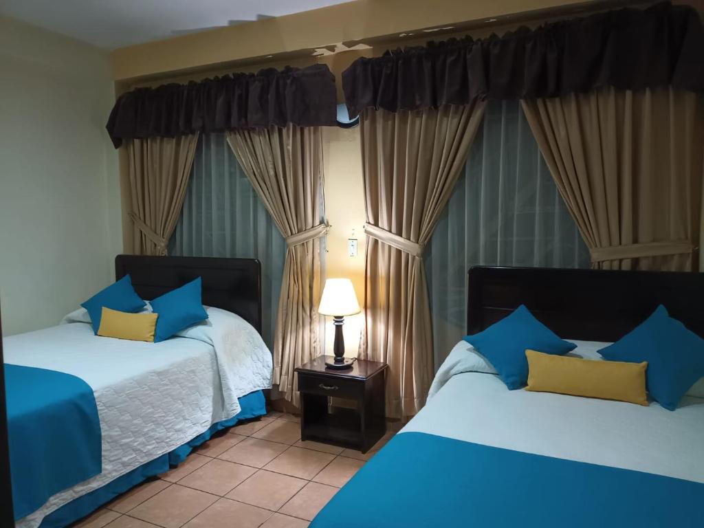 a bedroom with two beds with blue and yellow pillows at Crysol Center Hotel in Chimaltenango