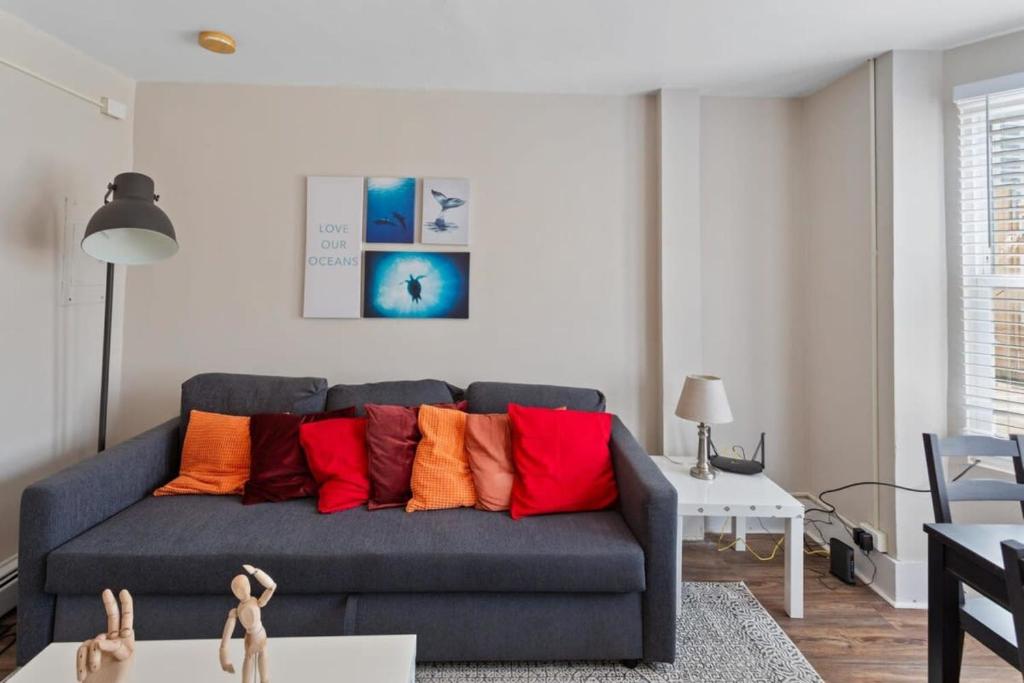 a living room with a blue couch with colorful pillows at 5BR Beach Block Orange Loop Steps from Boardwalk in Atlantic City
