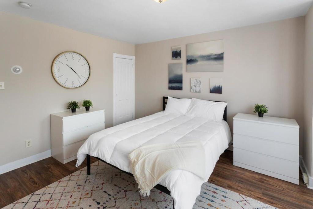 a bedroom with a large bed with a clock on the wall at 5BR Beach Block Orange Loop Steps from Boardwalk in Atlantic City