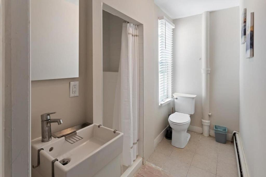 a white bathroom with a sink and a toilet at 5BR Beach Block Orange Loop Steps from Boardwalk in Atlantic City