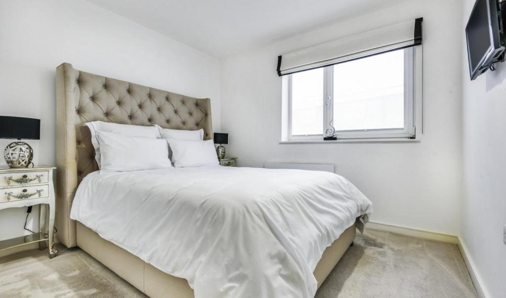 a white bedroom with a large bed and a window at Tower Bridge Lux-Penthouse in London