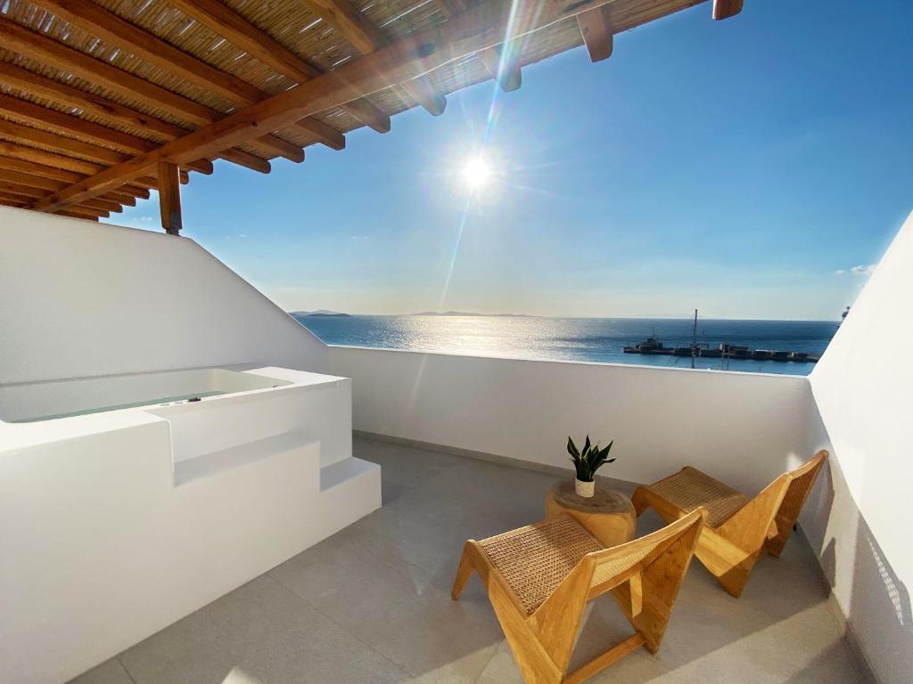 a balcony with two chairs and a view of the ocean at Calistus Mykonos in Mýkonos City