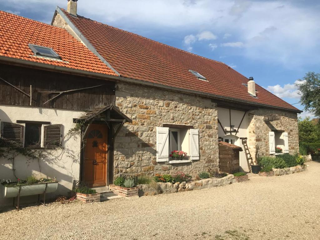 ein altes Steinhaus mit rotem Dach in der Unterkunft La Grange Aux Fleurs in Rigny-la-Nonneuse
