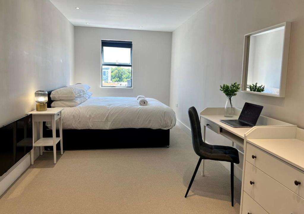 Schlafzimmer mit einem Bett und einem Schreibtisch mit einem Laptop in der Unterkunft Margate Beach Front Apt With Sea Views Sleeps 6 in Kent