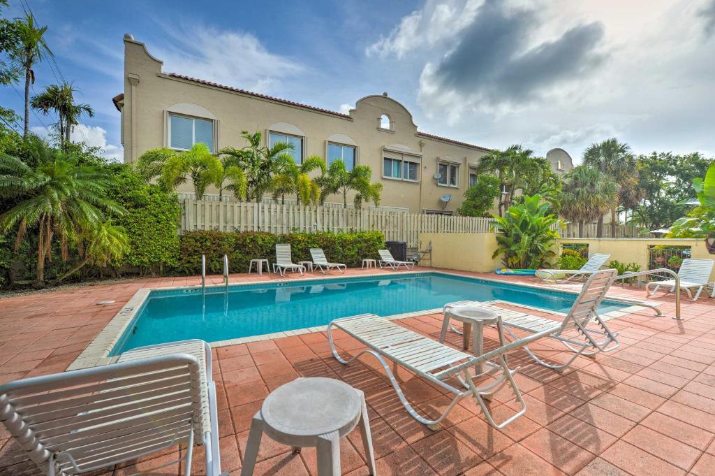 a swimming pool with chairs and a house at Ft Lauderdale Area Condo - Walk to Beach and Shops! in Fort Lauderdale