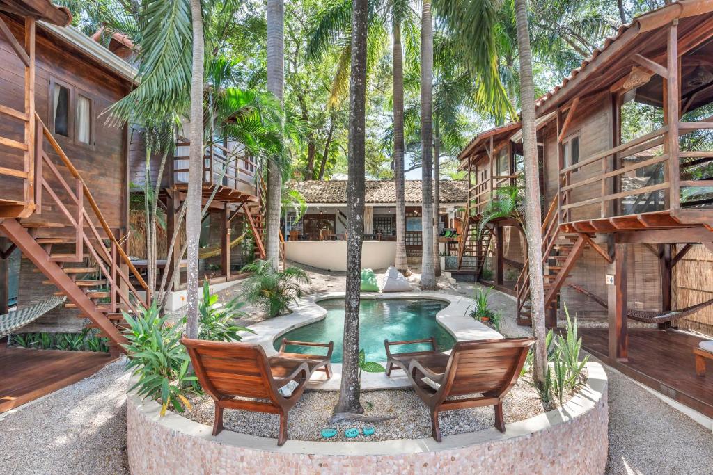 un patio trasero con piscina, 2 sillas y una casa en The Beach Bungalows - Yoga and Surf House - Adults Only en Tamarindo