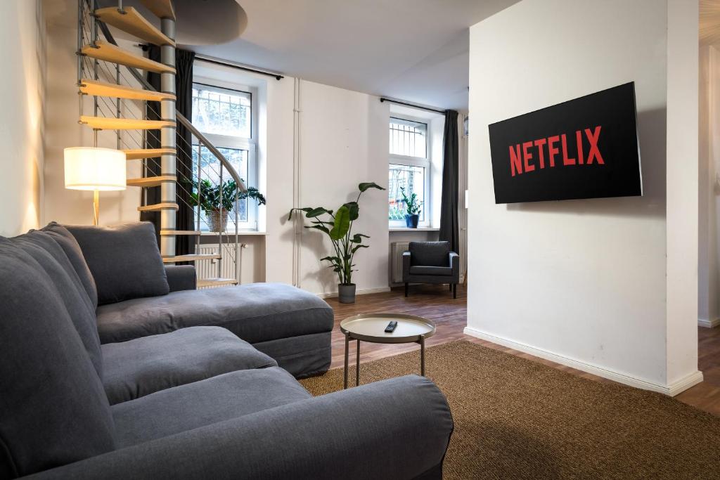 a living room with a couch and a tv on a wall at Sonnig & Helle Wohnung Alexanderplatz in 15min zu erreichen, Herthastraße sehr schön und groß für Gruppen geeignet in Berlin