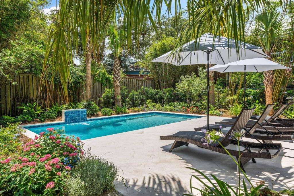 a swimming pool with two chairs and an umbrella at A Wave From It All - 811 Ocean Blvd in Saint Simons