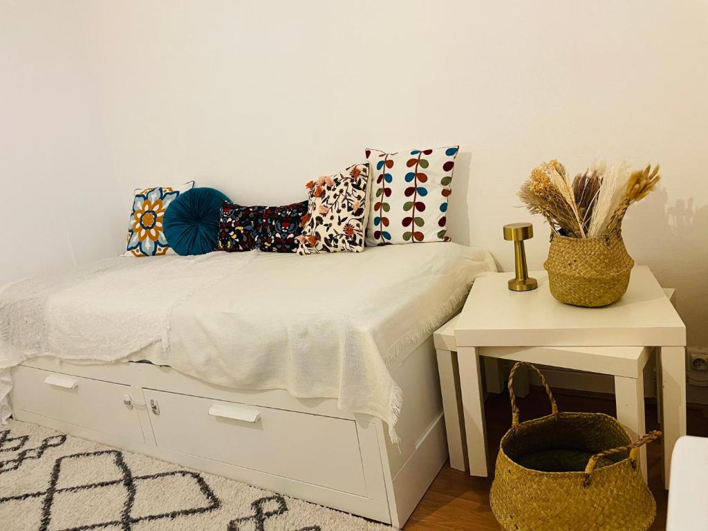 um quarto com uma cama branca com almofadas e uma mesa em Charmant studio 2 pièces em Grenoble