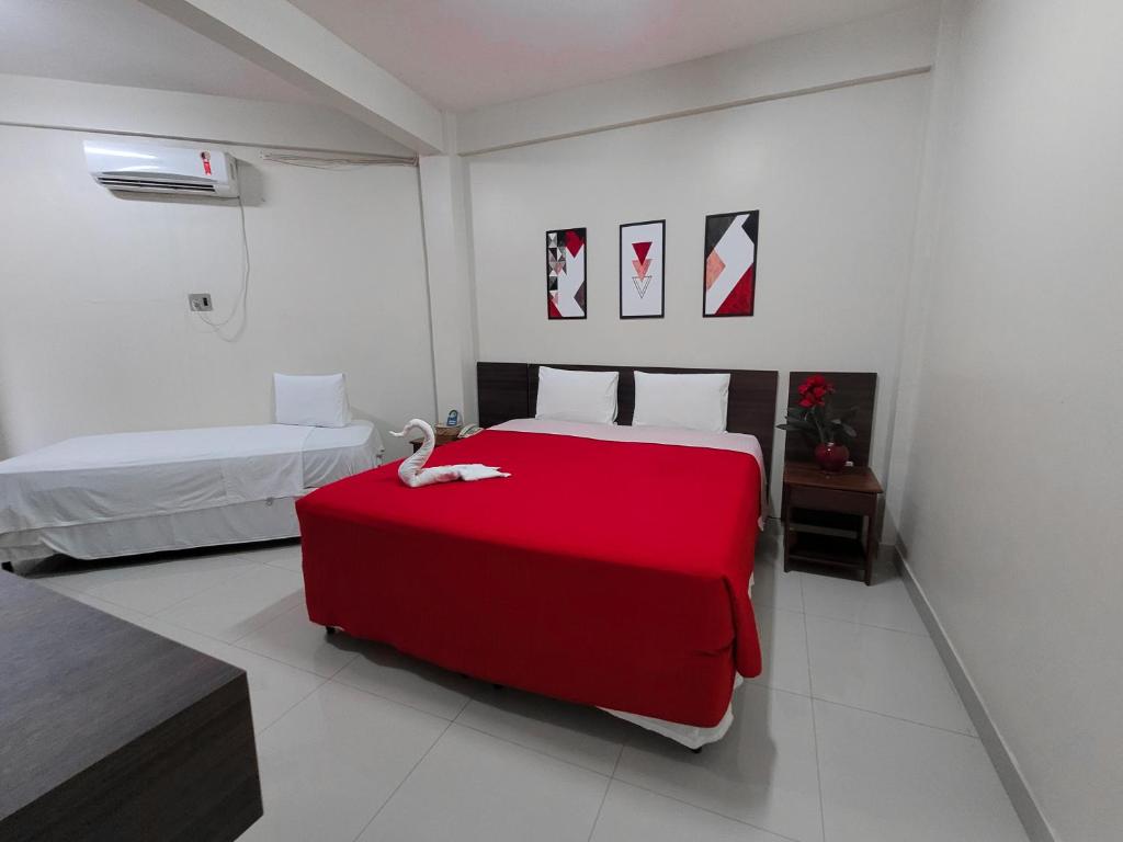 Un dormitorio con una cama roja con un cisne. en Carajas Hotel, en Parauapebas