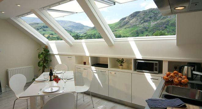 a kitchen with a table and chairs and windows at Buzzard's Reach formerly Rose Loft Coniston in Coniston