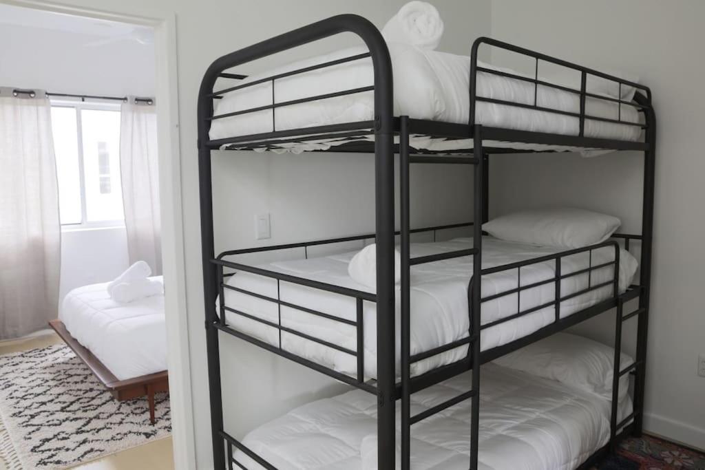 Zimmer mit 3 Etagenbetten mit weißer Bettwäsche in der Unterkunft Upscale 2BR Condo w Patio, City Views, Walk to DT Austin in Austin