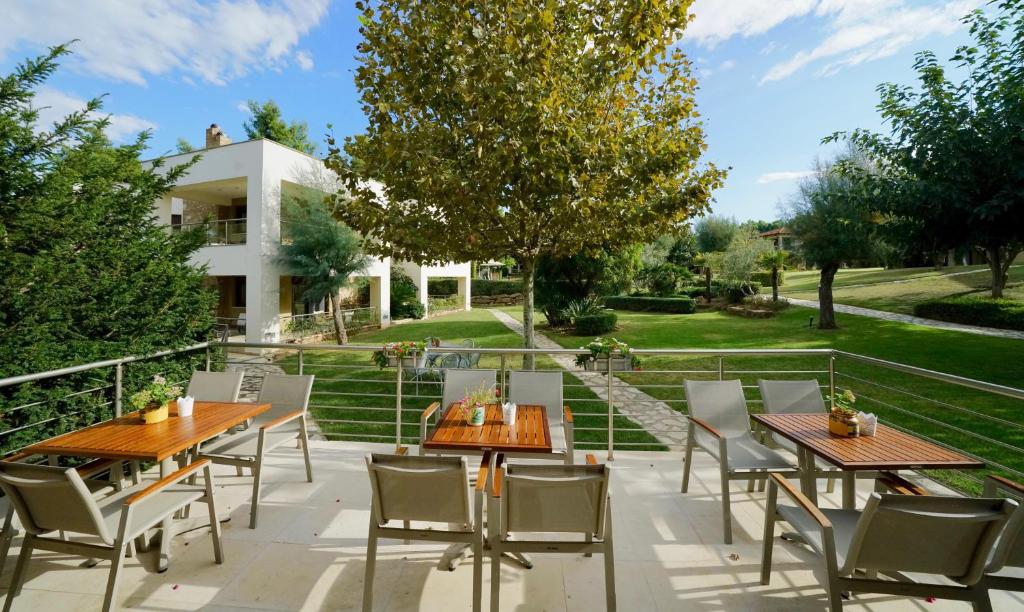 a patio with wooden tables and chairs in front of a house at Sani Polyastron Hotel & Spa in Sani Beach