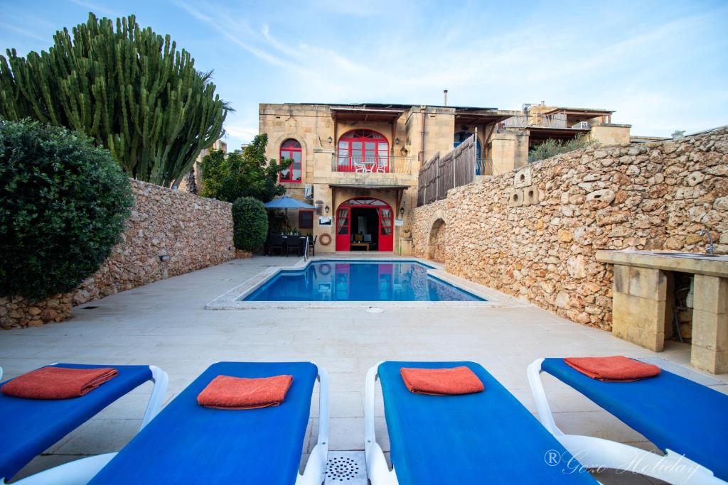 een villa met een zwembad en 2 blauwe ligstoelen bij Ta' Guza Holiday Home in Xagħra