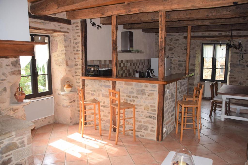 a kitchen with wooden stools in a stone house at Le four à pain in Najac