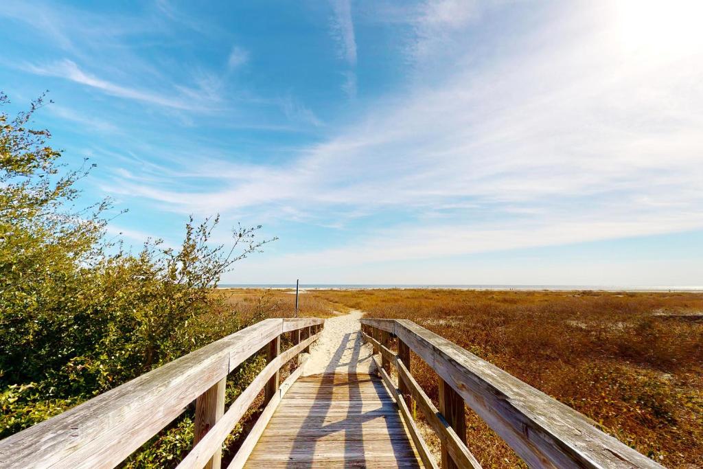a wooden bridge over a field with the sky at East Beach Villa Unit 204 in East End