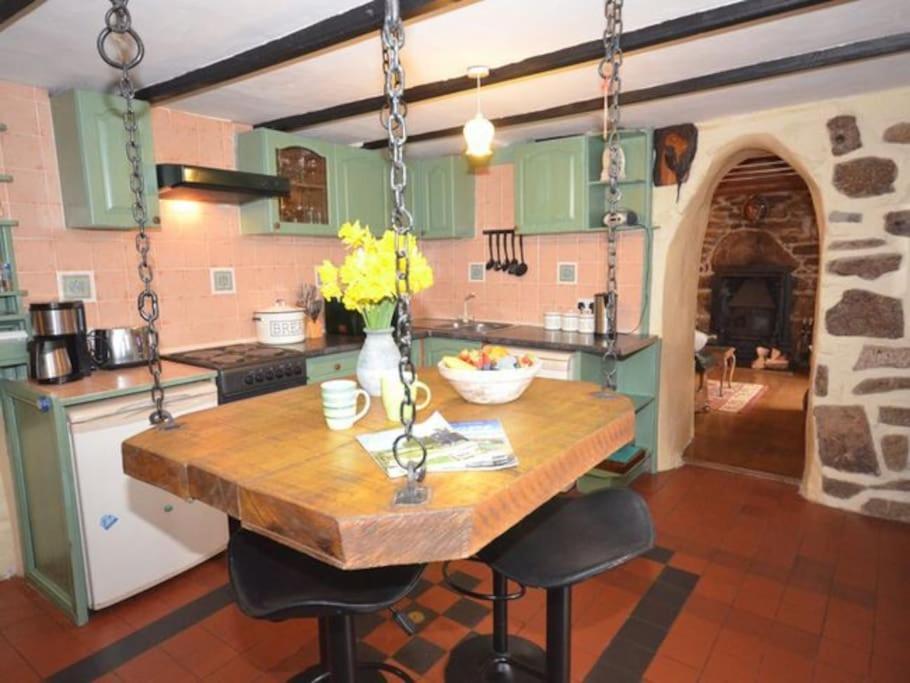 a kitchen with a wooden table and some chairs at Granite Country Cottage west of Penzance in Sancreed