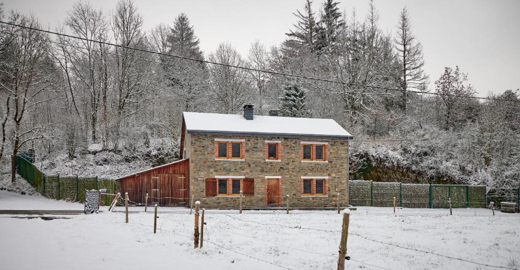 een huis in de sneeuw met een hek en bomen bij Le Rocher Du Lac in Houffalize