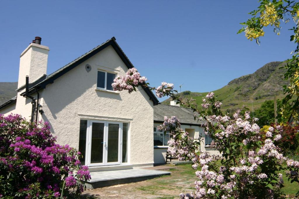 una casa blanca con flores delante en Cherry Tree Cottage Coniston, en Coniston