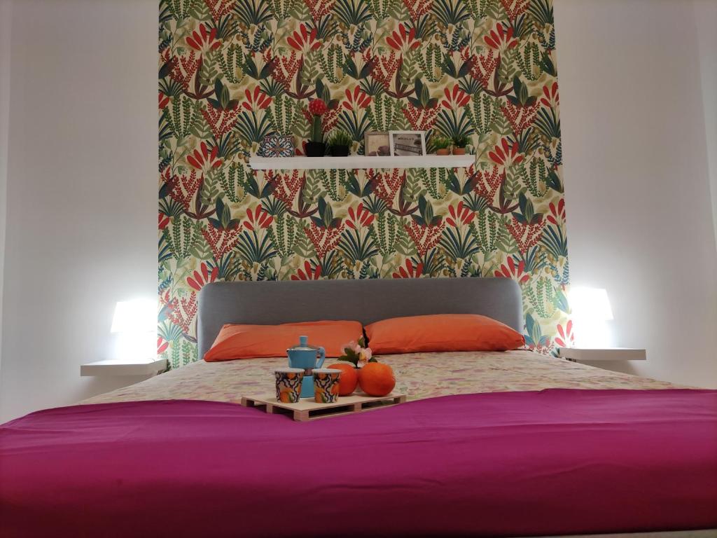 Dormitorio con cama morada y cabecero colorido en La Dimora Fiorita, en Catania