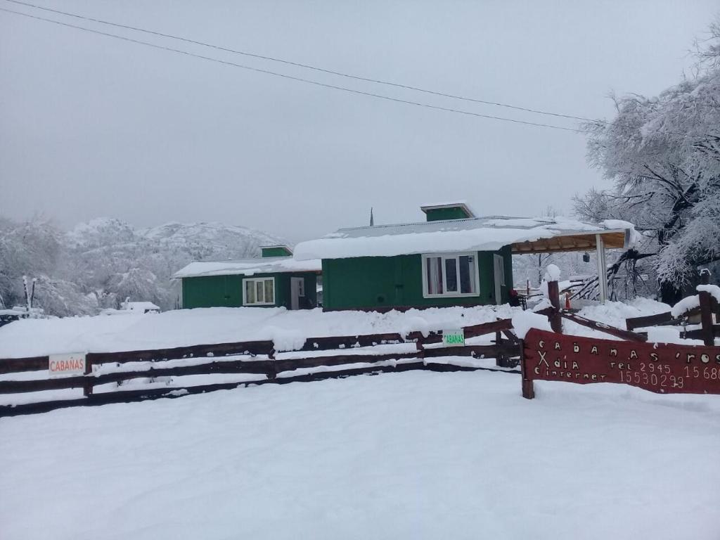 un patio de trenes cubierto de nieve con una casa verde en Cabañas Rosa en La Aldea