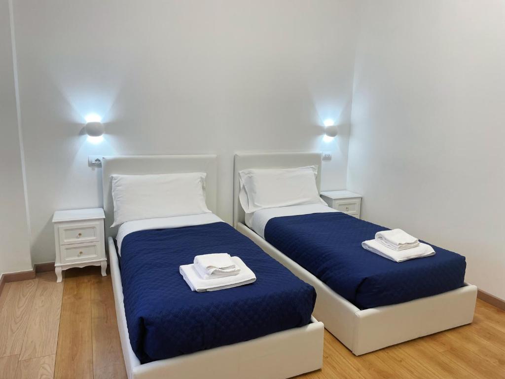 twee bedden in een kamer met blauwe lakens en handdoeken bij Nuovo Confortini Rooms in Verona