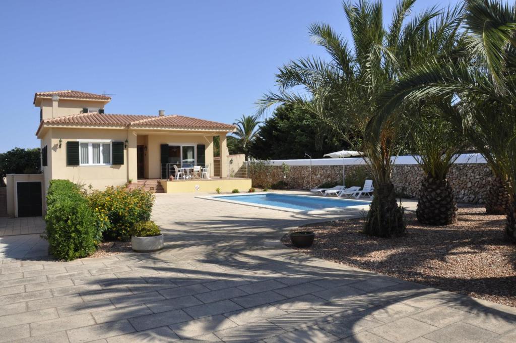 a house with a swimming pool and palm trees at Villa Francisca in Sa Caleta