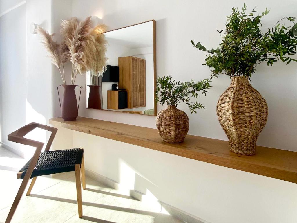 a mirror on a shelf with two vases and a chair at Calistus Mykonos in Mikonos