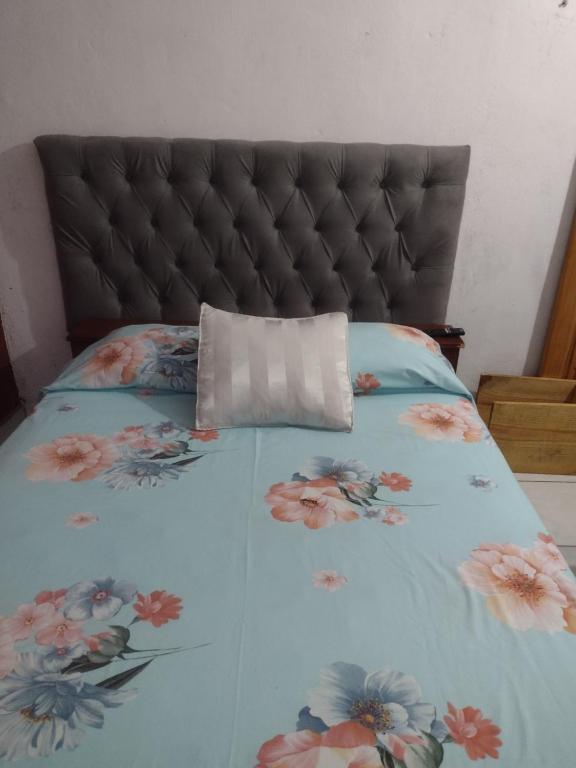 Una cama con un edredón azul con flores. en La posada del sol en Posadas