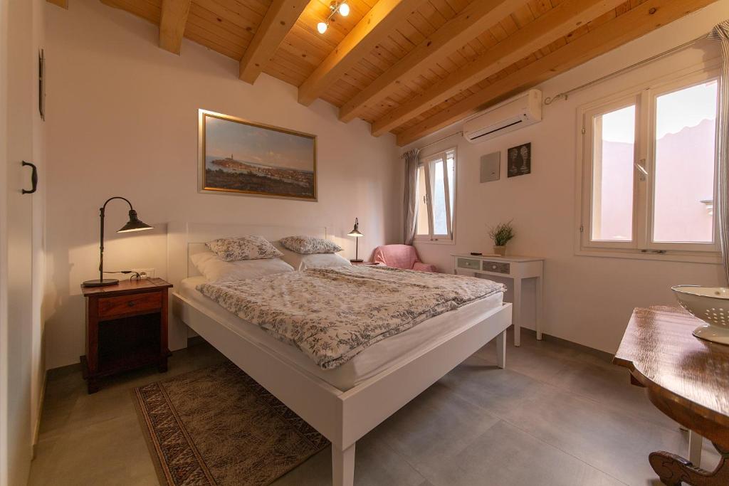 a bedroom with a bed and a table and windows at Apartments Casa Vecchia in Rovinj