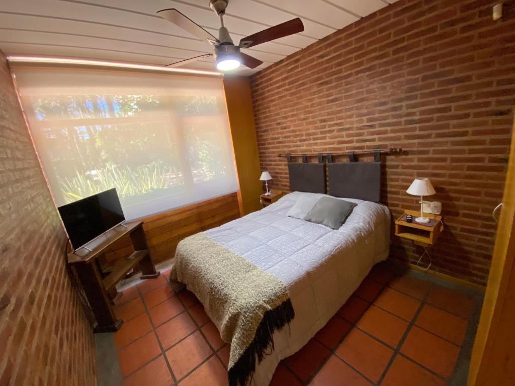 1 dormitorio con cama y pared de ladrillo en Avalon Aparts en Mar de las Pampas